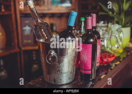 Teuer Champagner Flaschen in einer Metallschüssel auf dem Eis stehen auf Wein Holzfass. Eimer Wein Flaschen auf einen Hinterhof Partei. Das Schießen mit Stockfoto