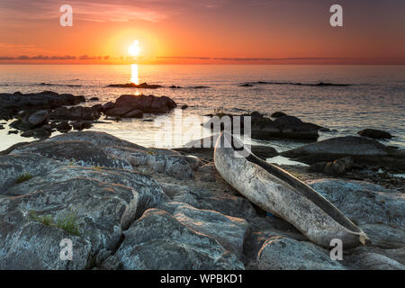 Sonnenaufgang Blick auf den Lake Malawi, Wellen glatt Rollen auf dem Strand, Holz- ein Baum Boot im Vordergrund, Afrika, Stockfoto