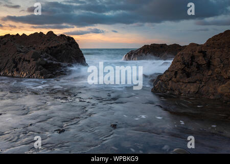 Wellen über die Felsen am Westward Ho! Strand in North Devon, Großbritannien Stockfoto