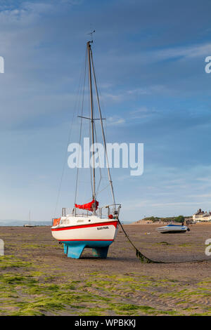 Die Sonne scheint auf einer Yacht bei instow Beach, North Devon mit Menschen in der Ferne genießen den Strand Stockfoto