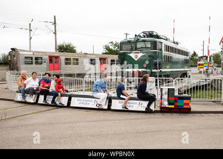 Besucher fahren mit dem Mini Express-Miniaturzug um die Ausstellung Railway Panorama im Museum Cité du Train in Mulhouse, Frankreich Stockfoto