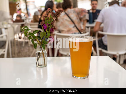 Pint cool IPA am weißen Tisch mit Blumen in Lissabon Bar oder Cafe Stockfoto