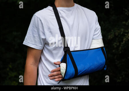 Mann mit gebrochenen Arm gewickelt Medizinische cast Gips und blauen verband. Fiberglas cast für das Handgelenk, Arm, Ellenbogen nach Sport Unfall, bei Bl isoliert Stockfoto
