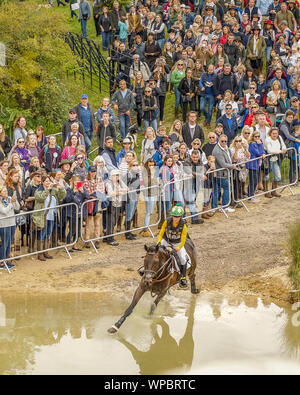 Cross country Pferd und Reiter galoppieren Sie den Hügel hinunter und in das Wasser an den Burghley Horse Trials Stockfoto