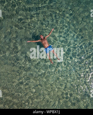 Chubby guy Schwimmen im Meer Antenne Stockfoto