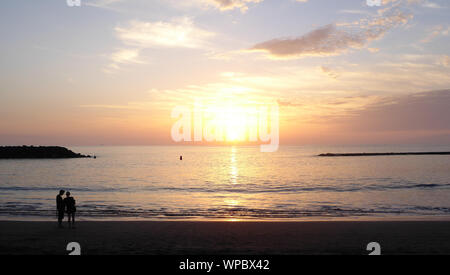 Paar beobachten Sonnenuntergang am Strand Stockfoto