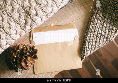 Pine Cone, Umschlag mit dem leeren Blatt und Leuchten, warmen gestrickten Pullover Festlegung auf den Tisch. Ansicht von oben, kopieren. Warme braun gemütlichen Farben. Stockfoto