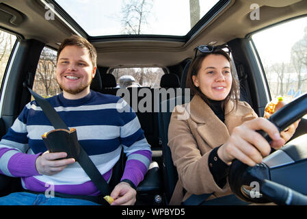 Junges Paar essen fast food im Auto. Stockfoto