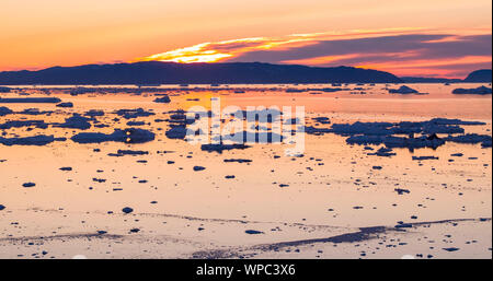 Eis und Eisberge vom Gletscher - Faszinierende arktische Natur Landschaft Luftbild der eisfjord mit Eisberge schmelzen Gletscher Sermeq Kujalleq, Ilulissat, Grönland gefüllt. Fischerboot und Mitternachtssonne. Stockfoto