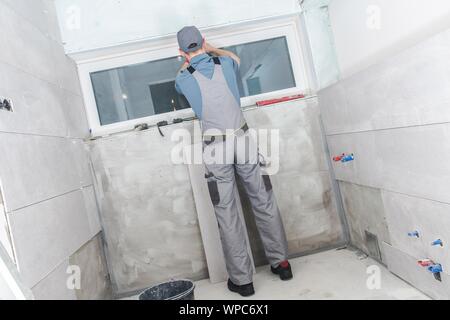 Bad Renovieren Job. Kaukasische Bauarbeiter, der Einbau neuer Fenster im Badezimmer. Stockfoto