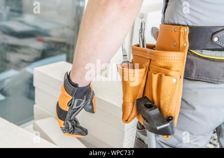 Auftragnehmer Arbeiter Tools Riemen Nahaufnahme. Bauindustrie Konzept. Kaukasische Builder vor Betonsteine. Industrielle Thema. Stockfoto