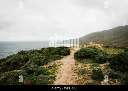 Der Weg in die Berge mit grünen Bürste, die zum Meer Stockfoto