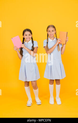 Alphabetisierung Club. Süße Kinder holding Bücher auf gelben Hintergrund. Kleine Mädchen mit Lexikon oder Bücher der Kinder. Pädagogische Bücher für Schulen. Bücher zu lesen. Schule Bibliothek. Homeschooling Konzept. Stockfoto