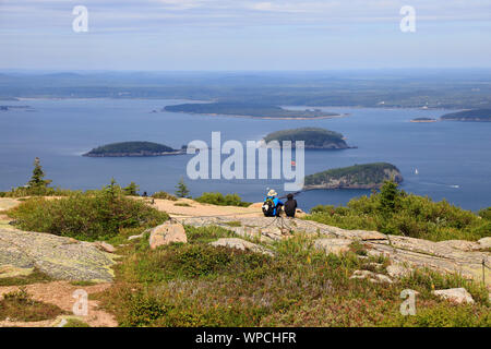 Besucher eine Pause auf der Oberseite des Cadillac Mountain mit Frenchman's Bay und Bar Harbor im Hintergrund. Acadia Nationalpark. Mount Desert. Maine. USA Stockfoto