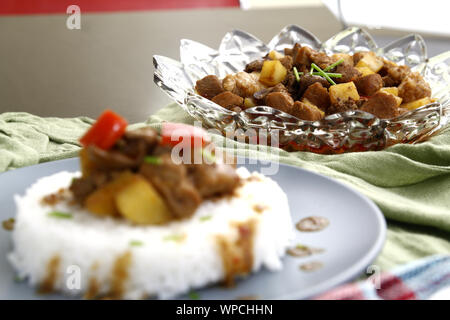 Foto der Philippinischen Gericht namens Menudo oder Schweinefleisch mit Kartoffeln und Rote Paprika in Tomatensauce gekocht Stockfoto