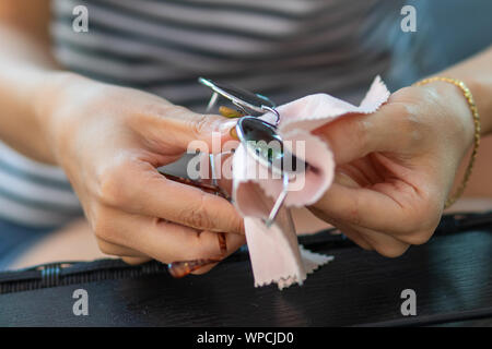 Frau Hände Reinigung Ihrer Sonnenbrille mit Mikrofasertuch wischen, wischen Sonnenbrille Stockfoto