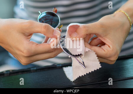 Wischen Sonnenbrille - Frau Hände Reinigung Ihrer Sonnenbrille mit Mikrofasertuch abwischen. Stockfoto