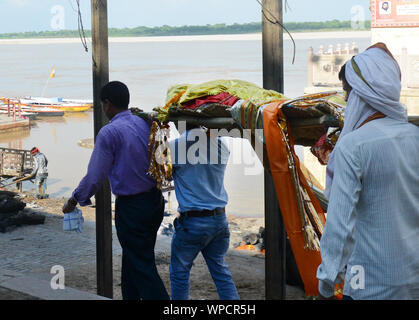 Männer, die einen toten Körper für feuerbestattung bei der feuerbestattung Ghat in Varanasi, Indien. Stockfoto