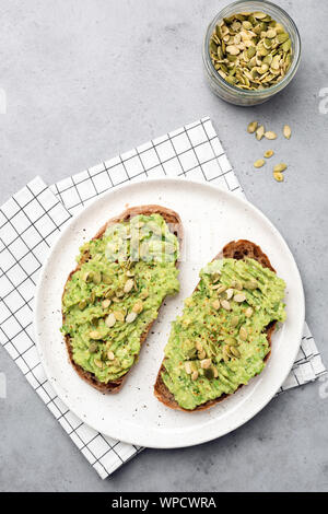 Gesundes Roggenbrot avocado Toast mit Samen auf weiße Platte. Tabelle Ansicht von oben Stockfoto