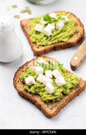 Zwei Scheiben Brot mit Guacamole und Feta. Toast mit Avocado und Käse. Gesunde Ernährung Stockfoto