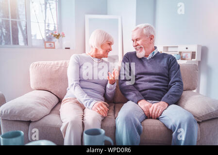Paar strahlende pensionierter Mann und Frau sitzt auf einem Sofa und chatten Stockfoto