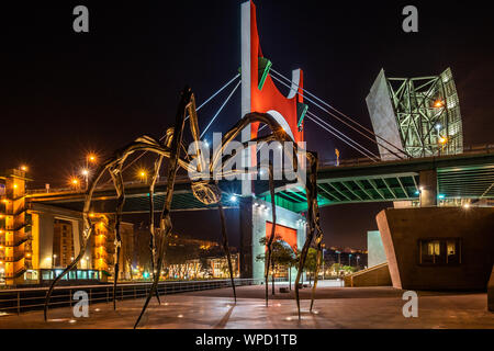 Nachtansicht von Maman Riesenspinne Skulptur auf dem Gehweg der Guggenheim Museum mit La Salve Brücke im Hintergrund, Bilbao, Baskenland, Spanien Stockfoto