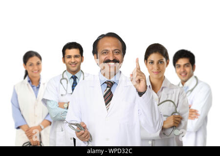 Team von medizinischen Fachkräften, geleitet von einem leitenden Arzt, der mit dem Zeigefinger steht Stockfoto