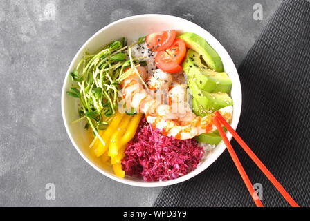 Frische Meeresfrüchte Rezept. Garnelen poke Schüssel mit Reis, Rotkohl, Avocado, gelbe Paprika. Essen Konzept poke Schüssel auf grauem Hintergrund Stockfoto