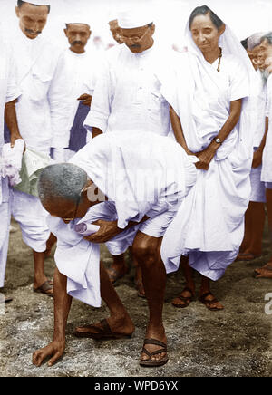 Mahatma Gandhi bricht das Salzgesetz, indem er einen Klumpen natürlichen Salzes aufnimmt, Dandi, Indien, 6. April 1930, Altes Vintage 1900s Bild