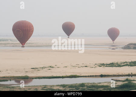 Bagan, Myanmar - März 2019: Heißluftballons Landung in der Nähe von Irrawaddy Fluss bei Sonnenaufgang Stockfoto