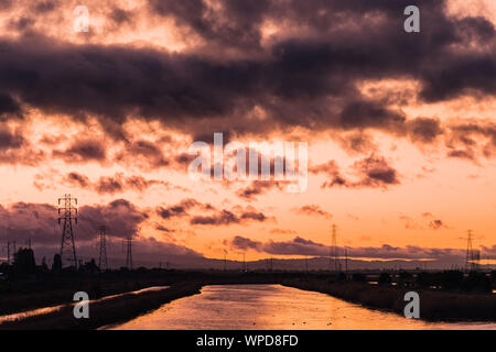 Feurigen Sonnenuntergang in San Francisco Bay Area mit hellem Sonnenlicht auf die Wasseroberfläche ein Bach wider, Sunnyvale, Kalifornien Stockfoto