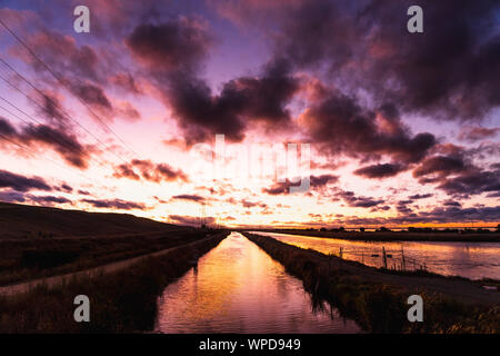 Feurigen Sonnenuntergang in San Francisco Bay Area mit hellem Sonnenlicht auf die Wasseroberfläche ein Bach wider, Sunnyvale, Kalifornien Stockfoto