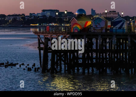 Globe Chrom auf einem bunten Regenbogen Hut auf Southend Pier, Southend On Sea, Essex, Großbritannien. Dämmerung, Sonnenuntergang über der Stadt am Meer. Ebbe, Bügeleisen Struktur Stockfoto