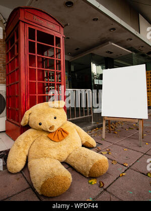 Ein riesiger Teddy sitzt neben einer roten Telefonzelle außerhalb eines Bridal shop in Taipei Stockfoto