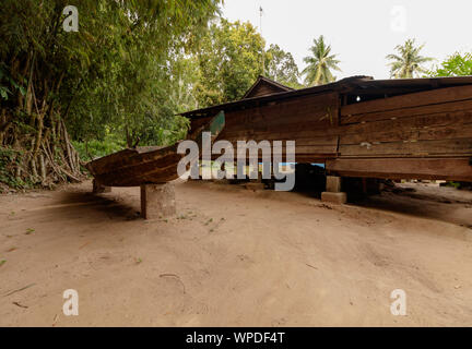Ein hölzernes Boot neben ein Holzhaus in Asien. Stockfoto