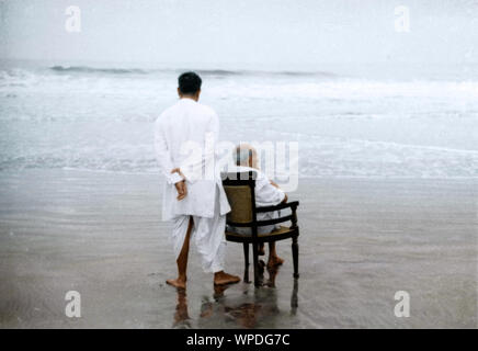 Mahatma Gandhi sitzt auf Stuhl und Devdas Gandhi am Juhu Beach, Bombay, Mumbai, Maharashtra Indien, Mai 1944 Stockfoto