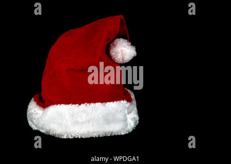 Ein weihnachten santa hut vor einem schwarzen Hintergrund isoliert Stockfoto