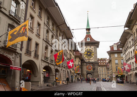 Bern, Schweiz - 7. Mai 2017: Street View der Kramgasse. Menschen gehen unter bunten Fahnen der Schweizer Kantone, Zytglogge Clock Tower ist auf einem Hintergrund Stockfoto