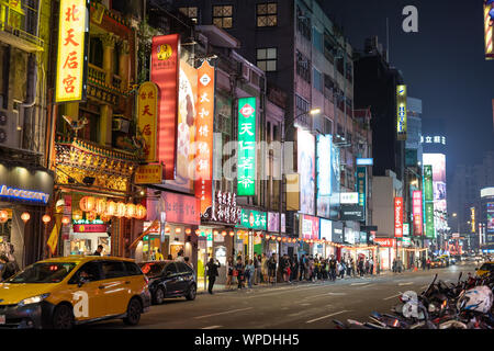 Taipei, Taiwan: Leere Urban Street in der Nacht beleuchtet durch bunte Werbung Leuchtreklame mit chinesischen Schriftzeichen. Die Menschen warten auf Bus, Taxi fahren durch. Stockfoto