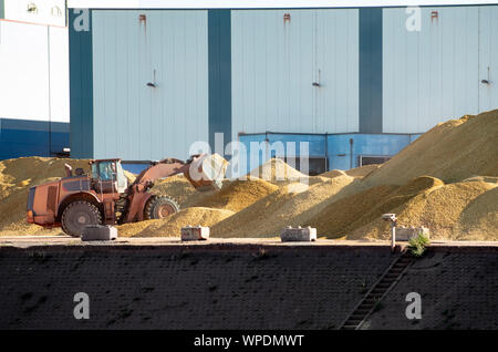 Riesige sand und kies Haufen vor Lager mit Bulldozer. Stockfoto