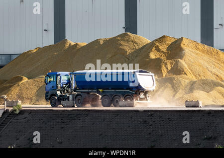 LKW fährt vor riesigen Sandpfählen auf einer Plattform. Stockfoto