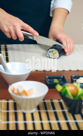 Köchin schneiden japanisches Sushi Roll Stockfoto