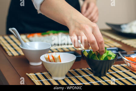 Koch Abholung in Scheiben Avocado Sushi zu machen Stockfoto