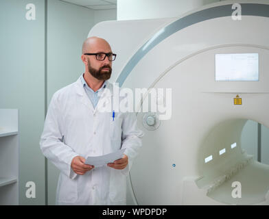 Arzt mit einem Patienten medizinische Karte in der Nähe von MRT-Scanner in einem Krankenhaus Stockfoto