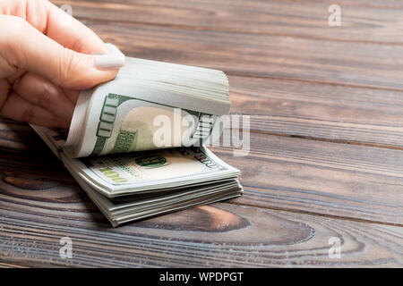 Perspektivische Ansicht der Hände eines Geschäftsfrau zählen Hundert Dollar Banknoten auf Holz- Hintergrund. Erfolg und Reichtum Konzept. Stockfoto