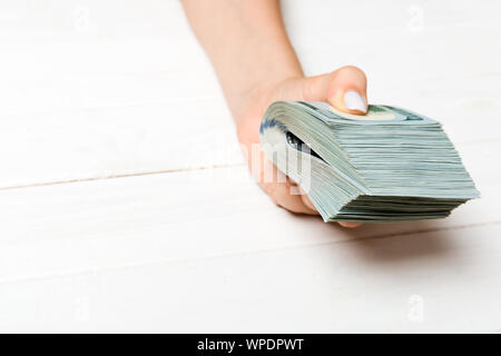 Perspektivische Ansicht der weiblichen Hand mit einem pack Geld für Holz- Hintergrund. Hundert Dollar. Geschäftskonzept. Nächstenliebe und Tipps Konzept. Stockfoto