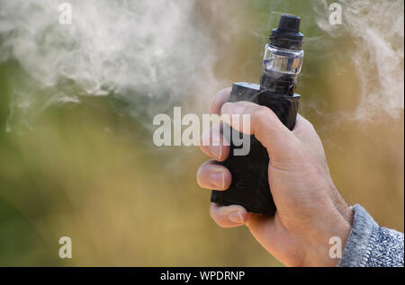 Ein vaping Mod in die Hand eines Mannes mit vaping Nebel Umgebung gehalten Stockfoto