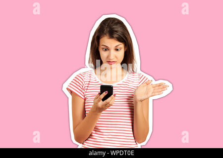 Schüler Mädchen in einem gestreiften Oberteil bekleidet, peinlich Blick in ein Smartphone in den Händen ratlos, verwirrt. emotionale Mädchen Zeitschrift co überrascht Stockfoto