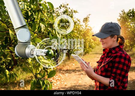 Bauer steuert Roboterarm mit einer Tablette. Smart Farming und digitale Transformation in der Landwirtschaft Stockfoto