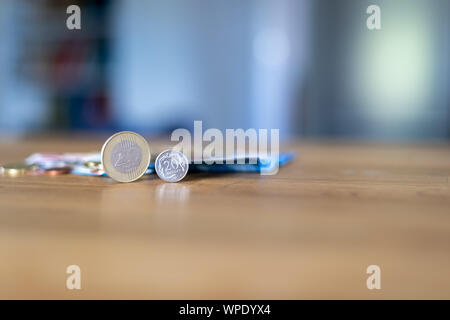 Euro-banknoten und -Münzen auf einen hölzernen Tisch. Verschwommen, unscharf Hintergrund. Bokeh. Stockfoto